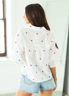Woman wearing a white blouse with star patterns on a beige background

