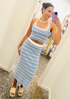Woman taking a mirror selfie wearing a blue and white striped dress in a store.