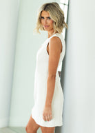 Woman wearing a white dress against a beige background

