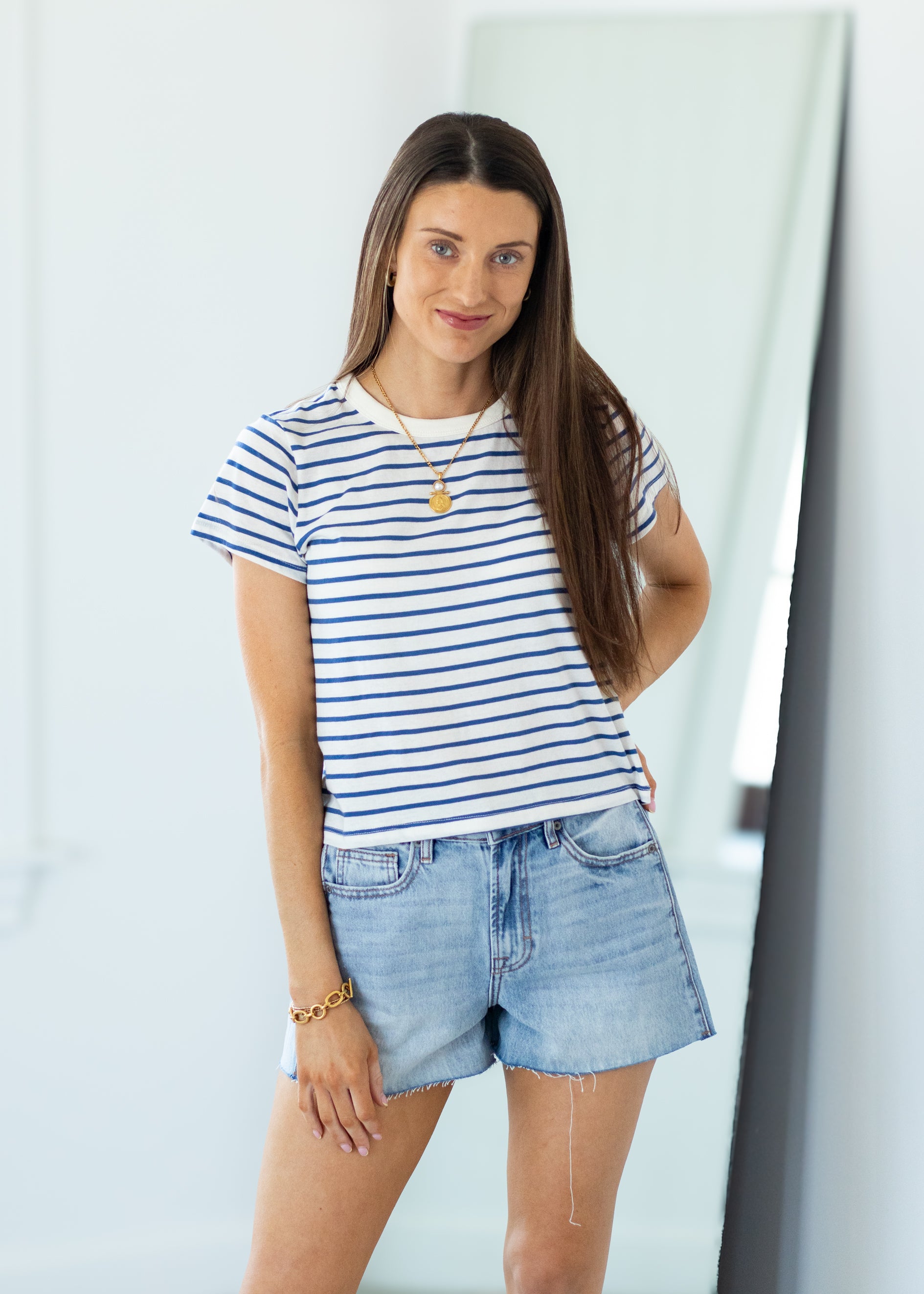 Woman wearing a striped shirt and denim shorts in an indoor setting
