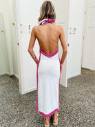 Woman wearing a white dress with pink trim in a room with white doors.