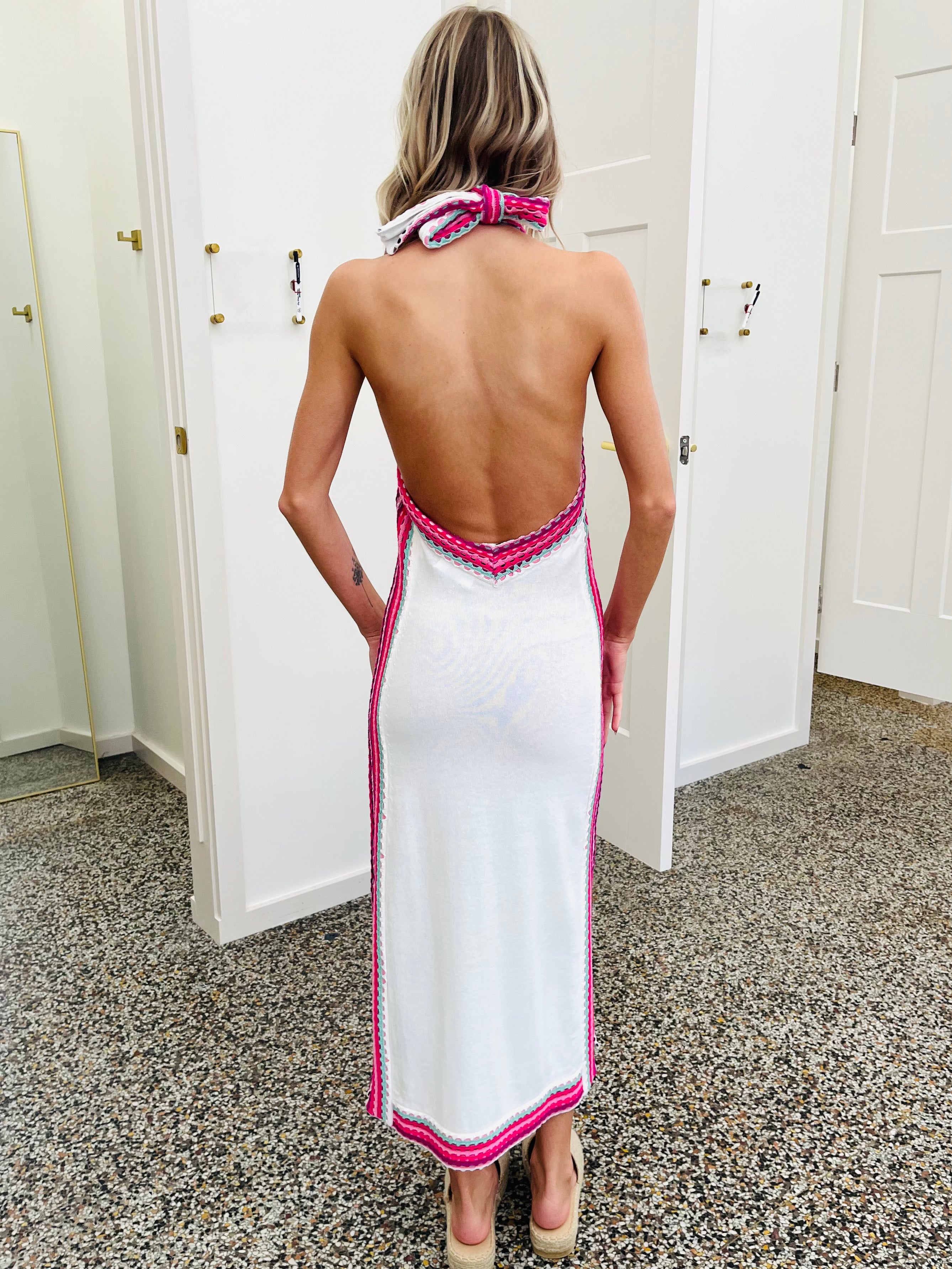Woman wearing a white dress with pink trim in a room with white doors.