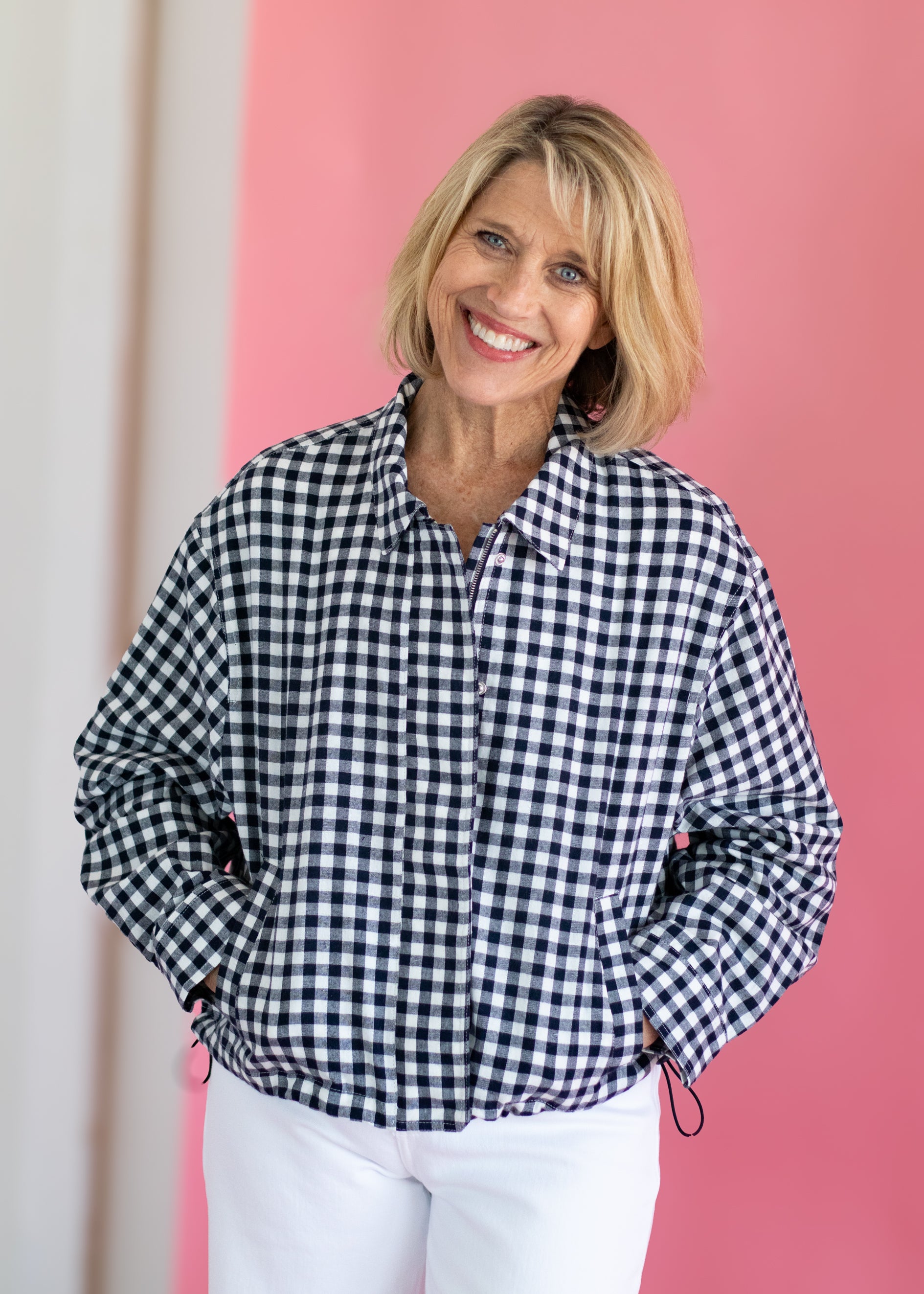 Woman wearing a black and white checkered shirt against a pink background