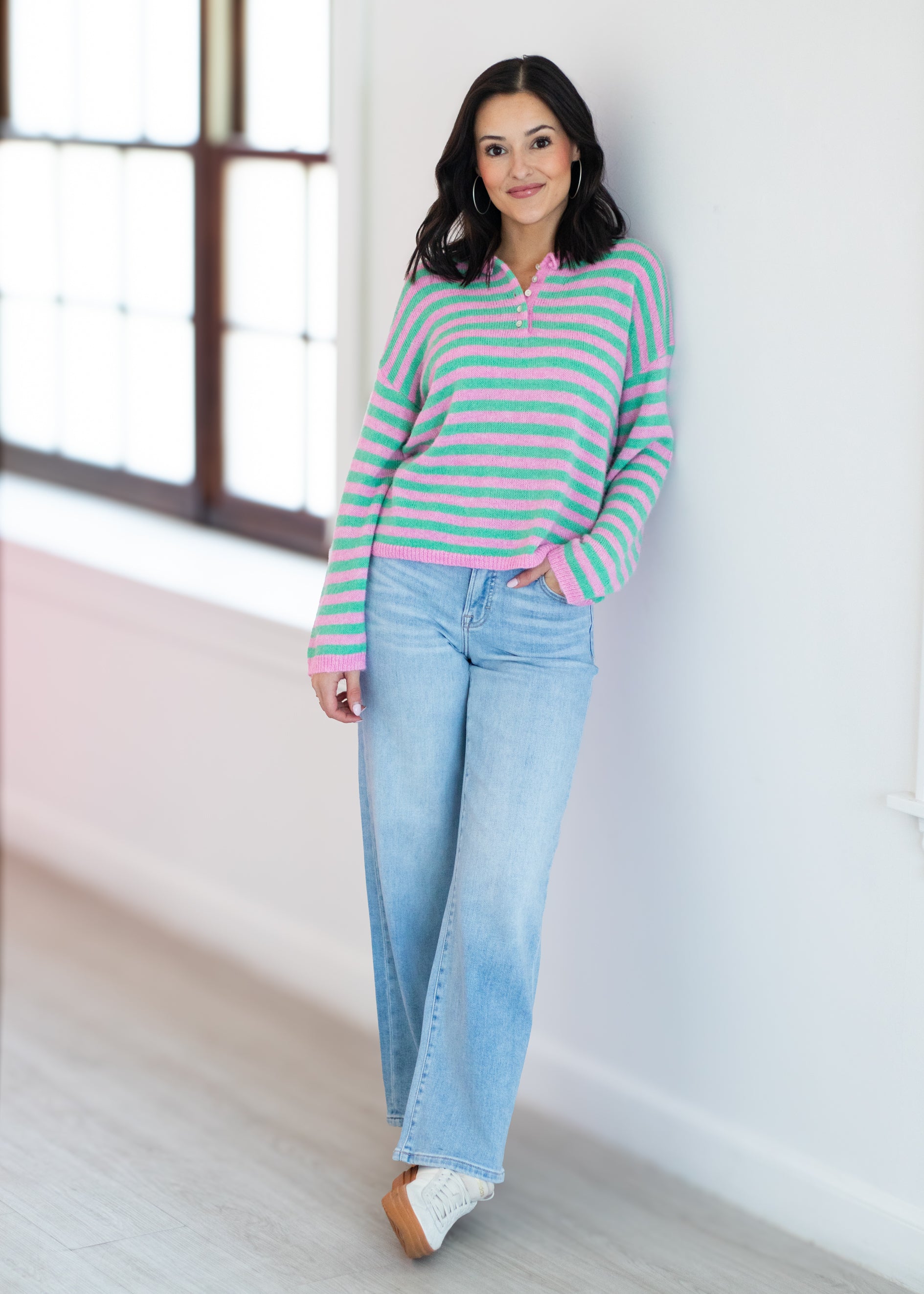 Woman wearing a striped sweater and jeans indoors.