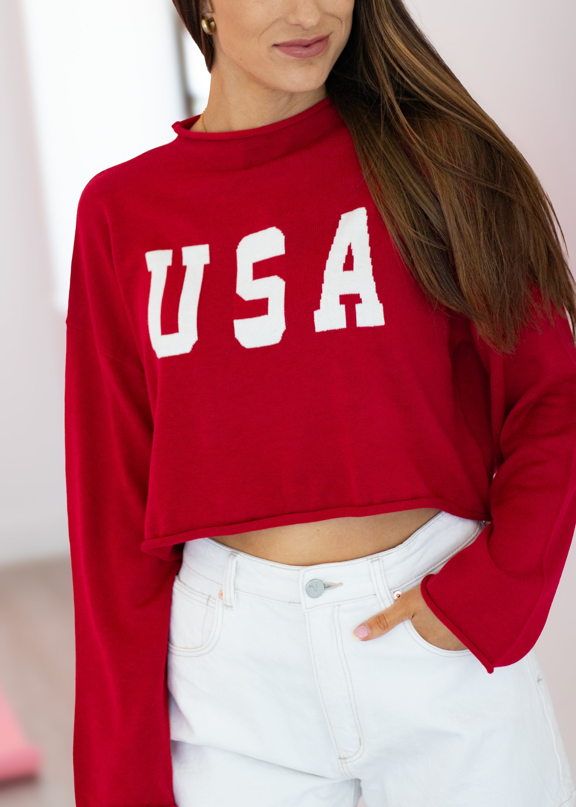 Person wearing a red 'USA' crop top with white pants against a neutral background