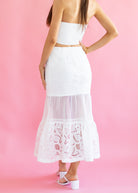White lace skirt worn by a person on a pink background