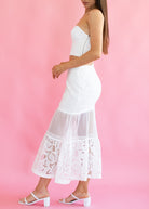 White dress with lace details on a pink background