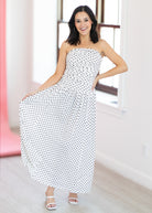 Woman wearing a strapless polka dot dress in a bright room.