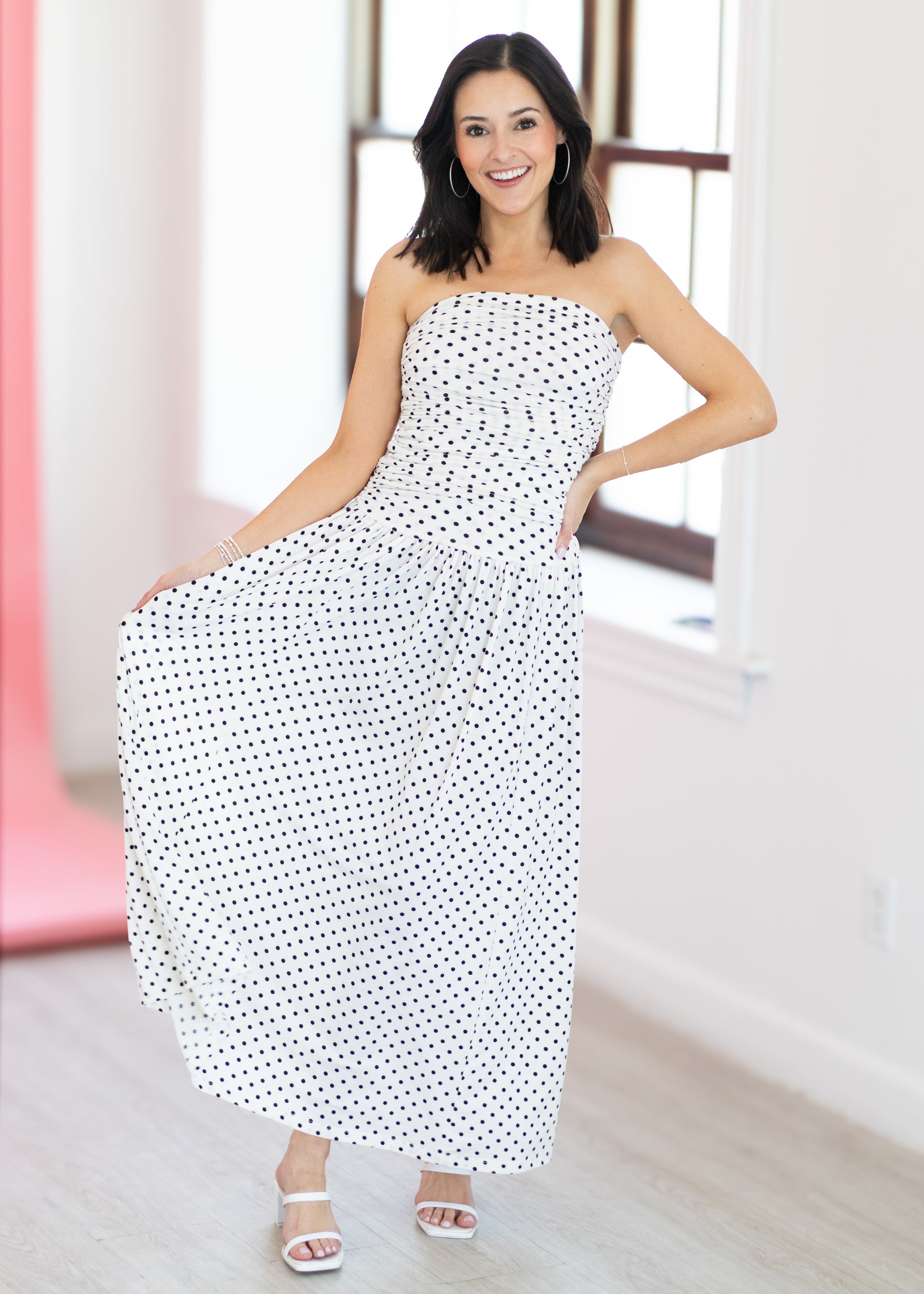 Woman wearing a strapless polka dot dress in a bright room.
