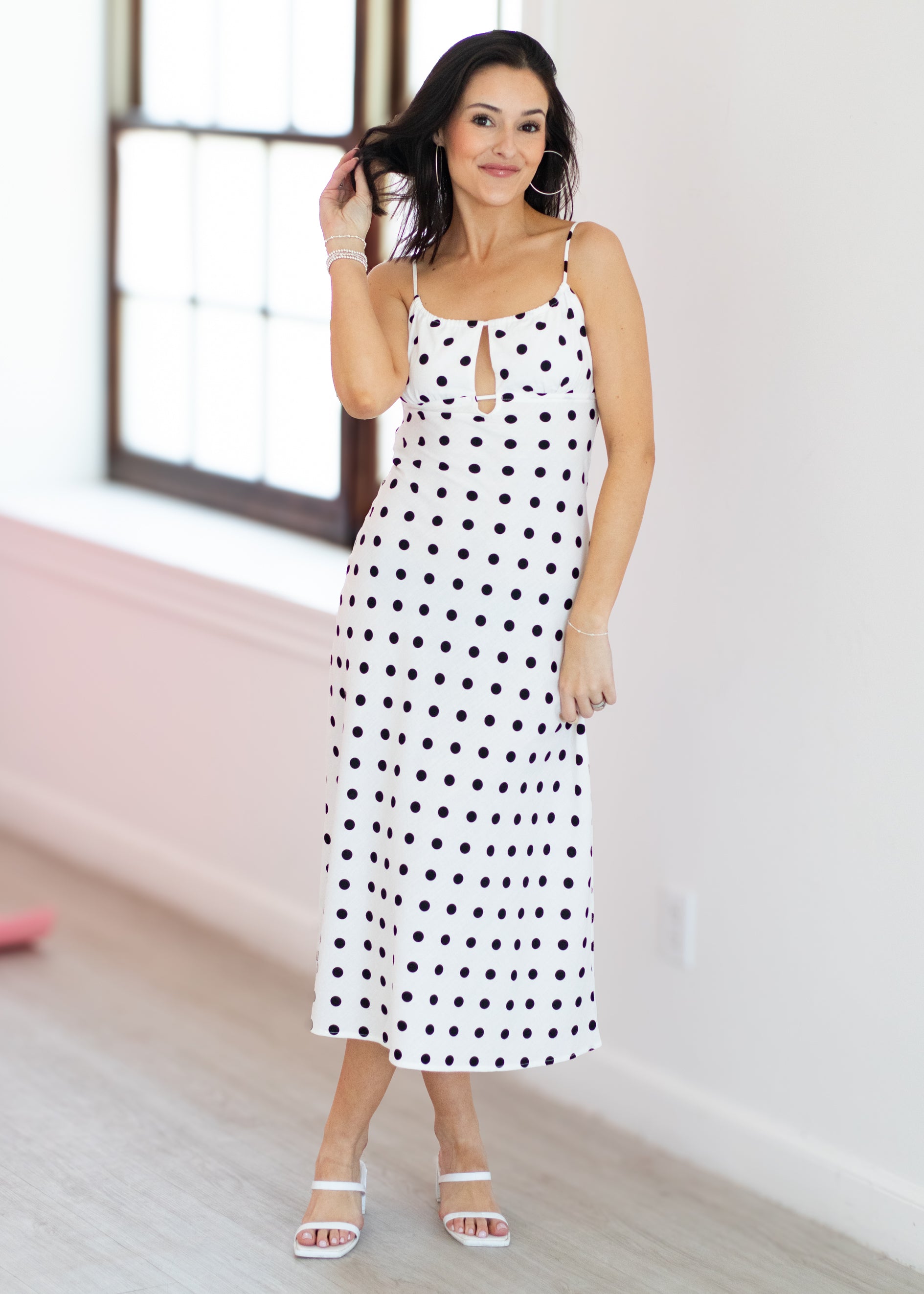 Woman wearing a polka dot dress in a room with a window.