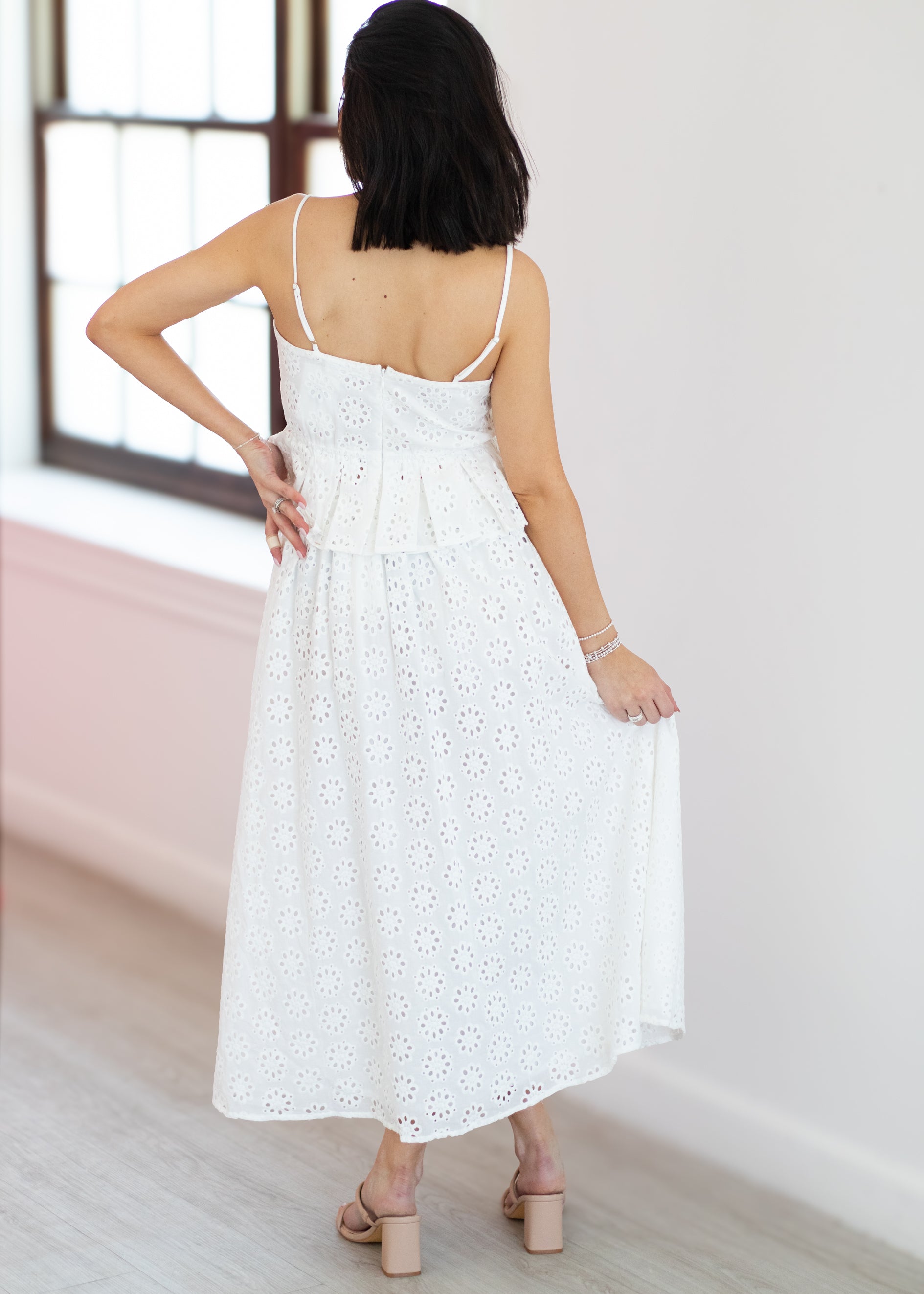 Woman wearing a white dress with thin straps in a minimal indoor setting