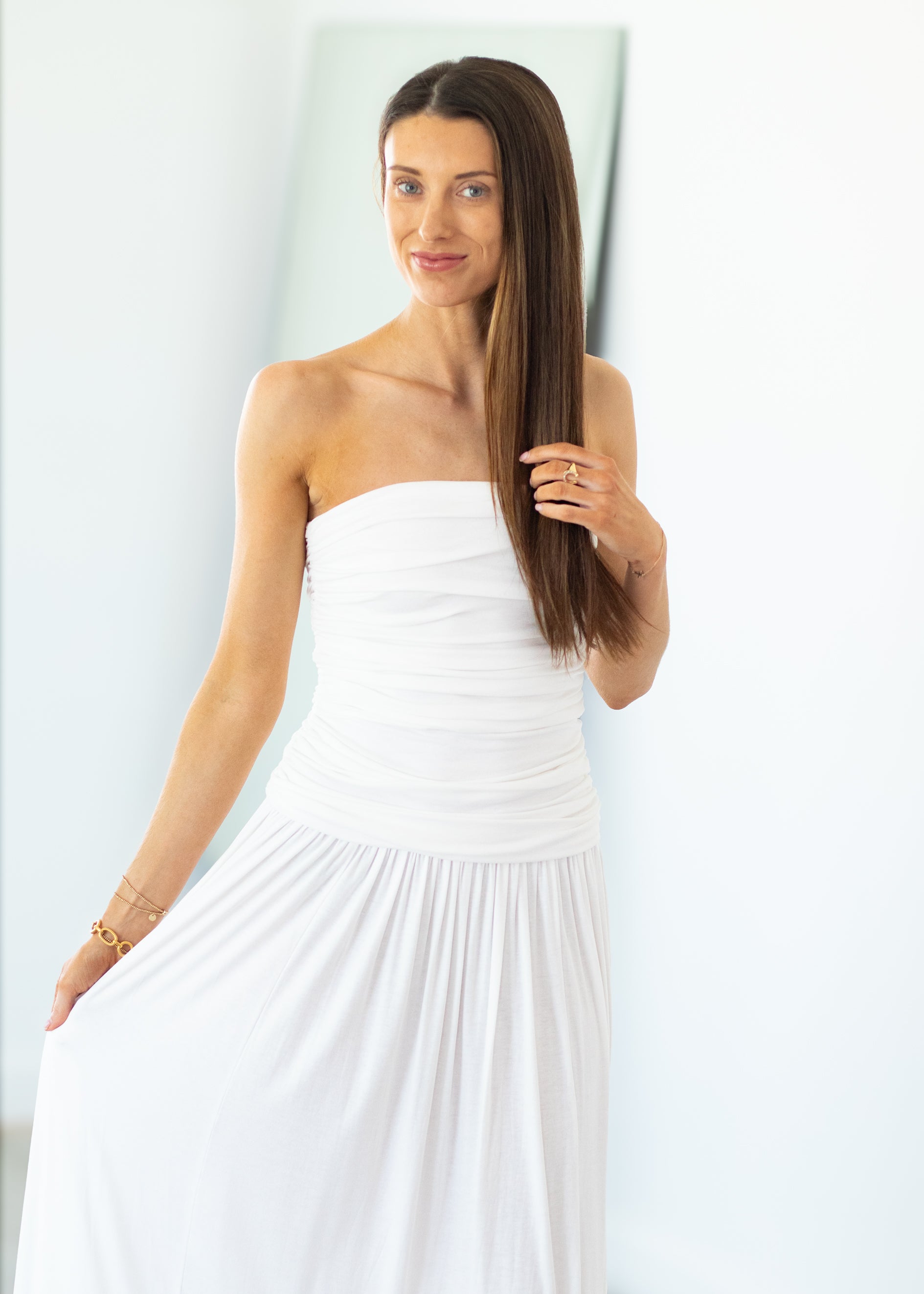 Woman wearing a strapless white dress against a light background