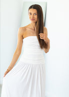 Woman wearing a strapless white dress against a light background