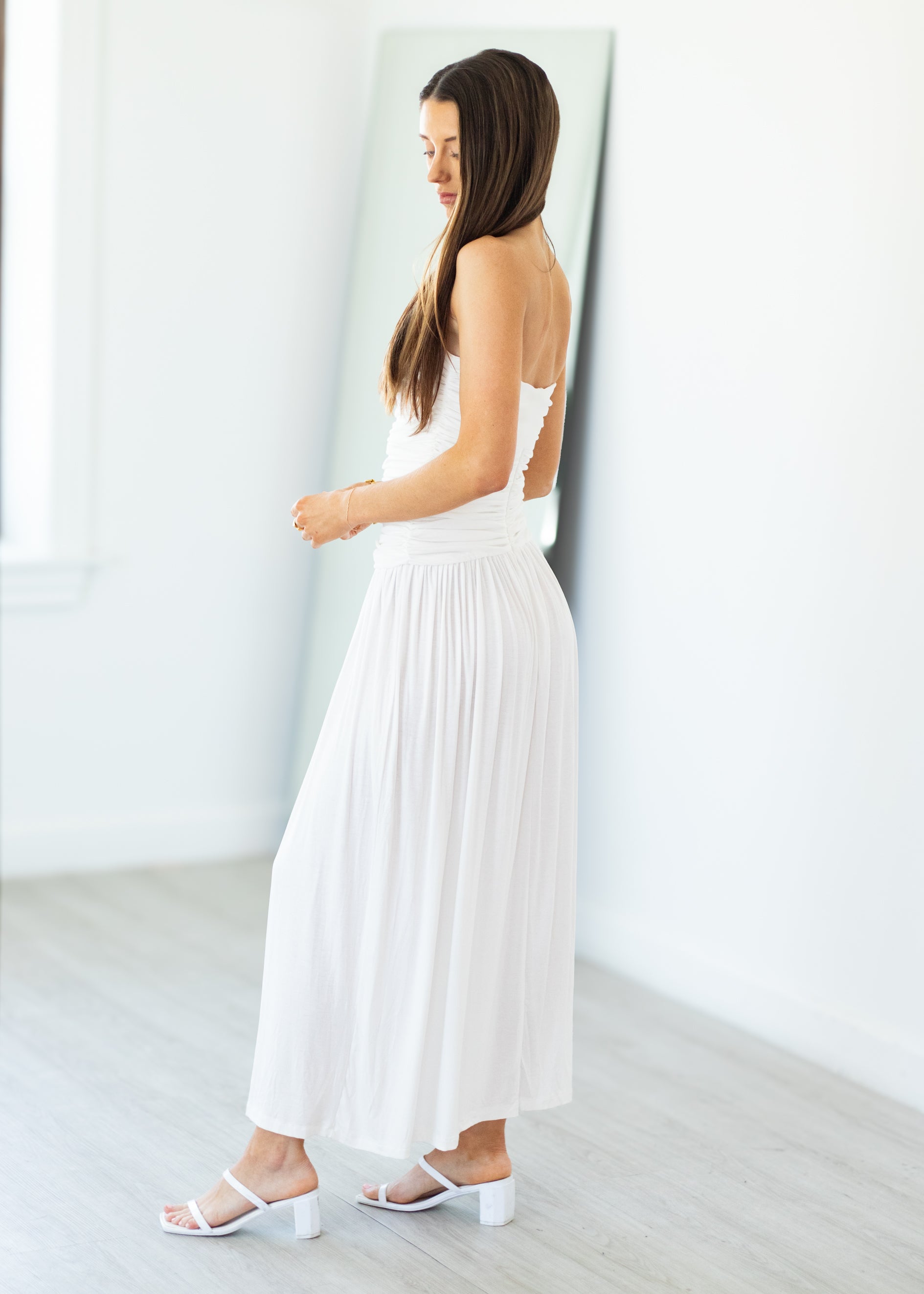 Woman wearing a white dress with cut-out shoulders in a minimalistic setting