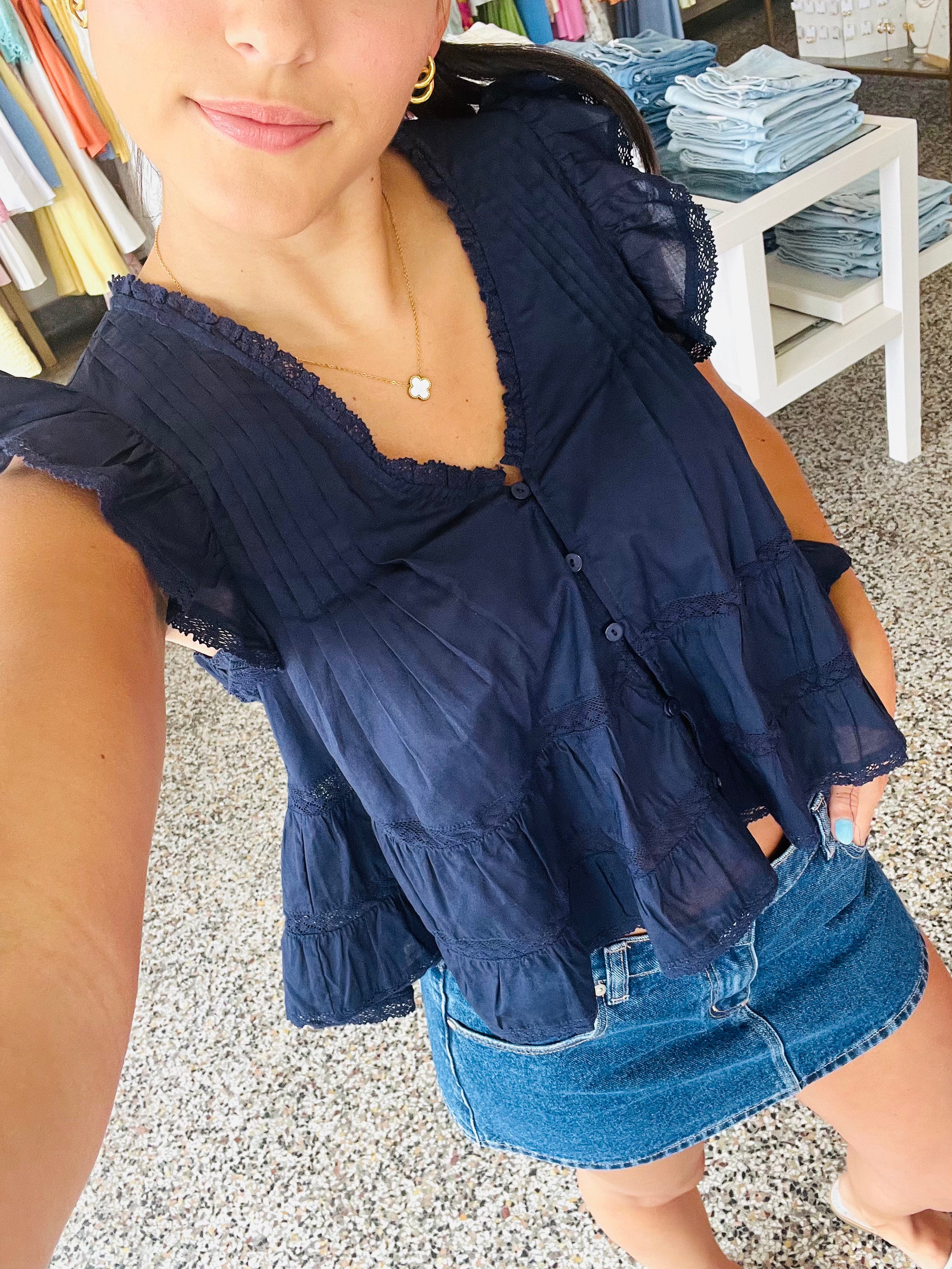Woman wearing a navy blue top and denim shorts in an outdoor setting.
