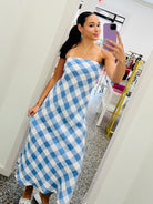 Woman taking a mirror selfie wearing a blue and white checkered dress.