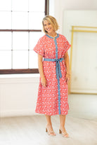 Woman wearing a red floral dress with a blue belt against a white background