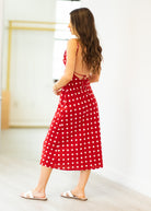 Woman wearing a red polka dot dress in a minimal indoor setting