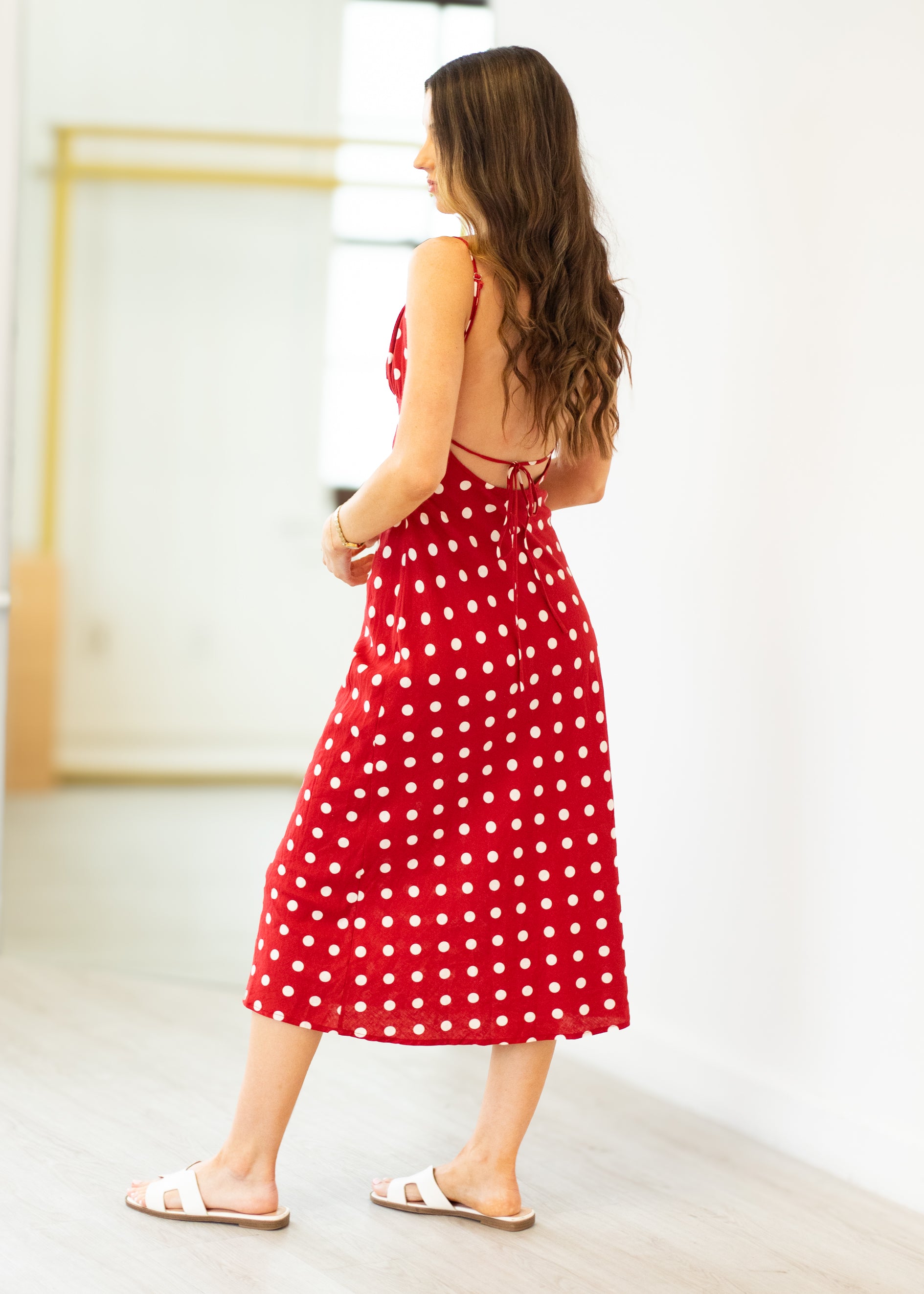 Woman wearing a red polka dot dress in a minimal indoor setting