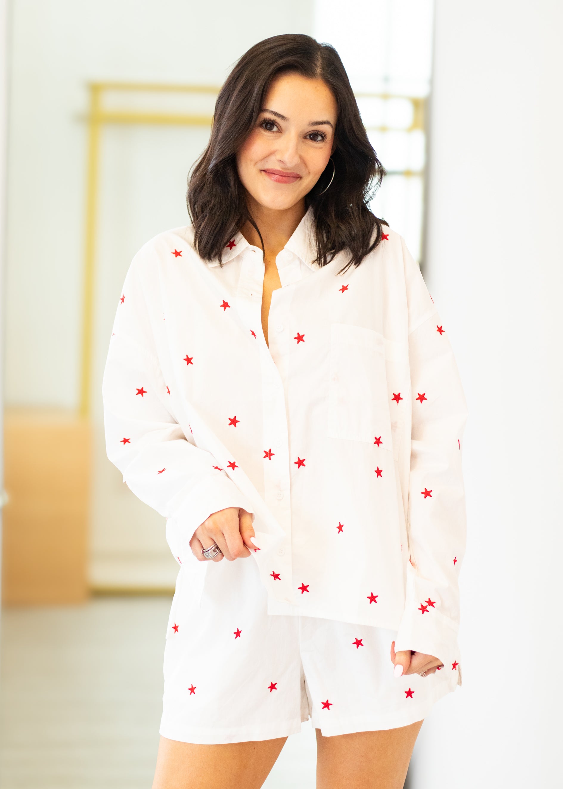 Woman wearing a white outfit with red star patterns in a minimal indoor setting