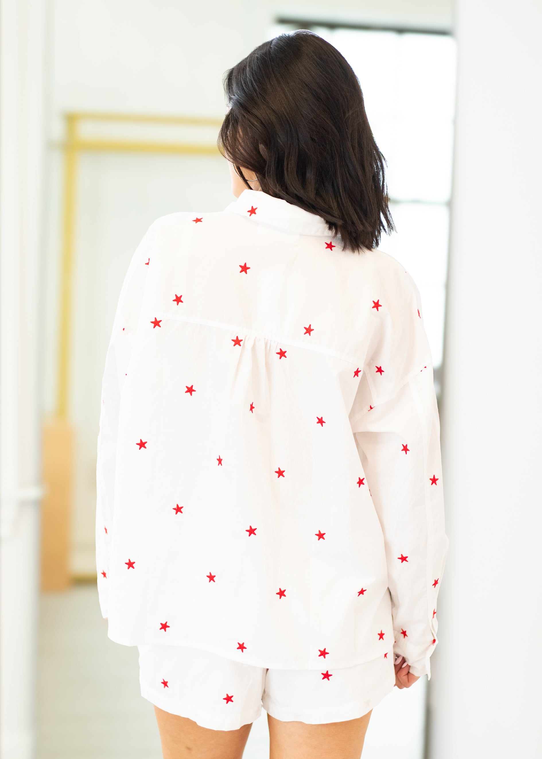 Person wearing a white outfit with red star patterns in a minimal indoor setting
