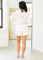 Person wearing a white outfit with red polka dots in a minimal indoor setting.