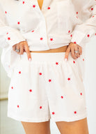 White outfit with red star patterns worn by a person on a white background