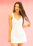 Woman wearing a white dress against a pink background