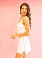 Woman wearing a white dress against a pink background