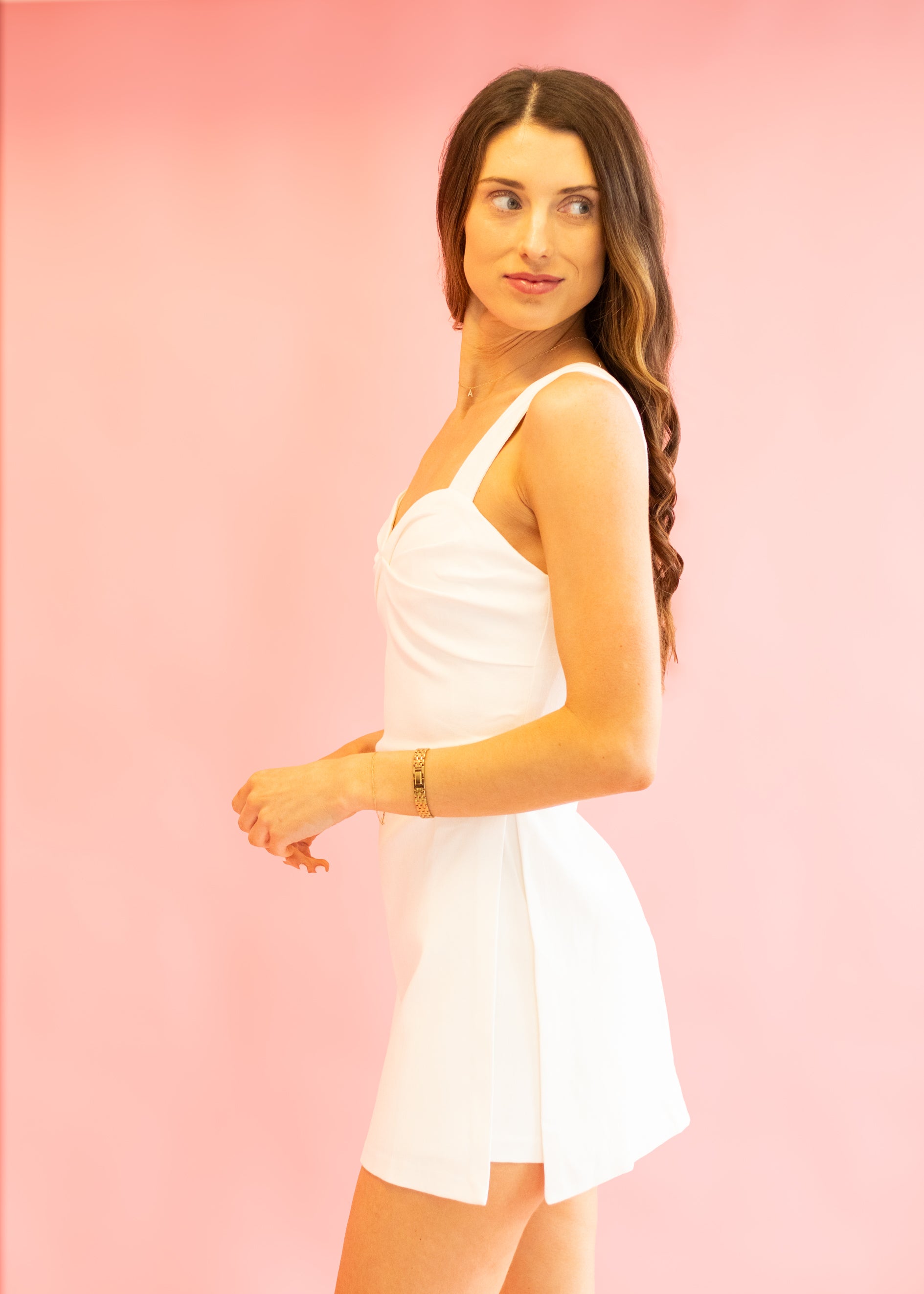 Woman wearing a white dress against a pink background