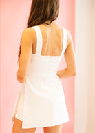 Woman wearing a white dress against a pink background