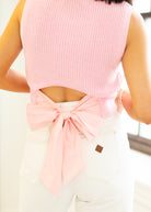 Pink sleeveless top with a bow detail worn by a person, blurred background