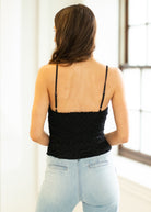 Woman wearing a black top and light blue jeans indoors.