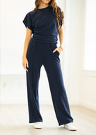 Woman wearing a navy blue outfit with wide-leg pants and a matching top in a bright room.