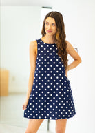 Woman wearing a navy blue dress with white polka dots indoors.