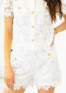White lace dress with gold buttons on a white background