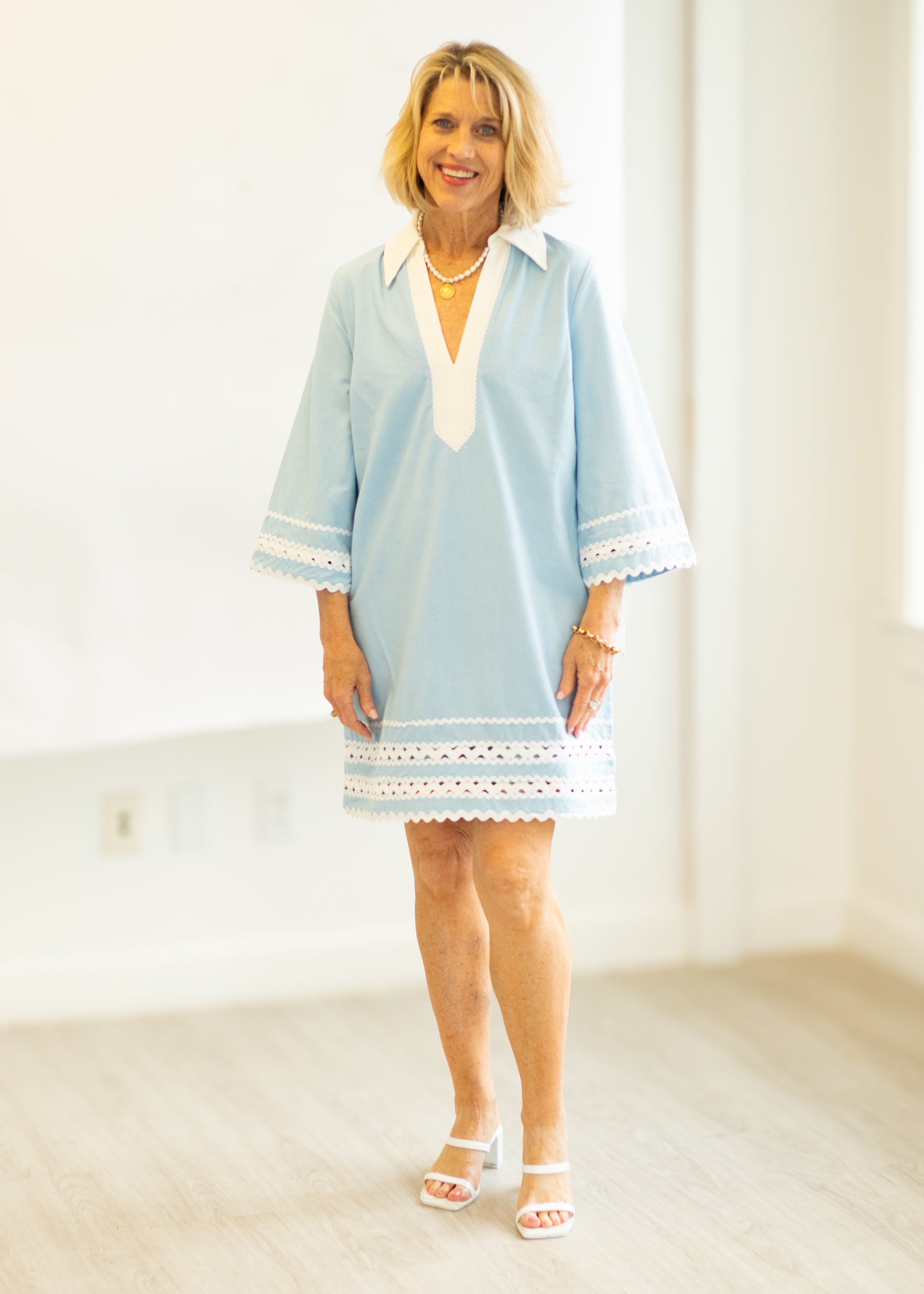 Woman wearing a light blue dress with white lace trim in a minimalistic setting