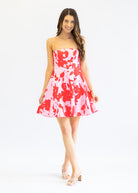 Woman wearing a red and white floral dress on a white background