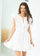 Woman wearing a white dress with embroidery in an indoor setting