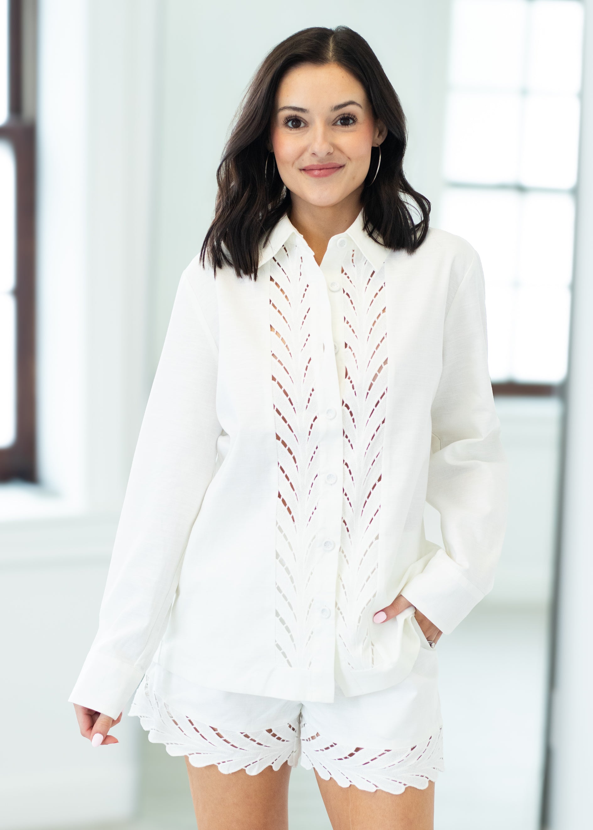 Woman wearing a white outfit with lace details in a bright room