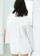 Person wearing a white outfit with lace details in a minimal indoor setting