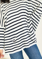 Close-up of a person wearing a black and white striped shirt with blue jeans on a white background