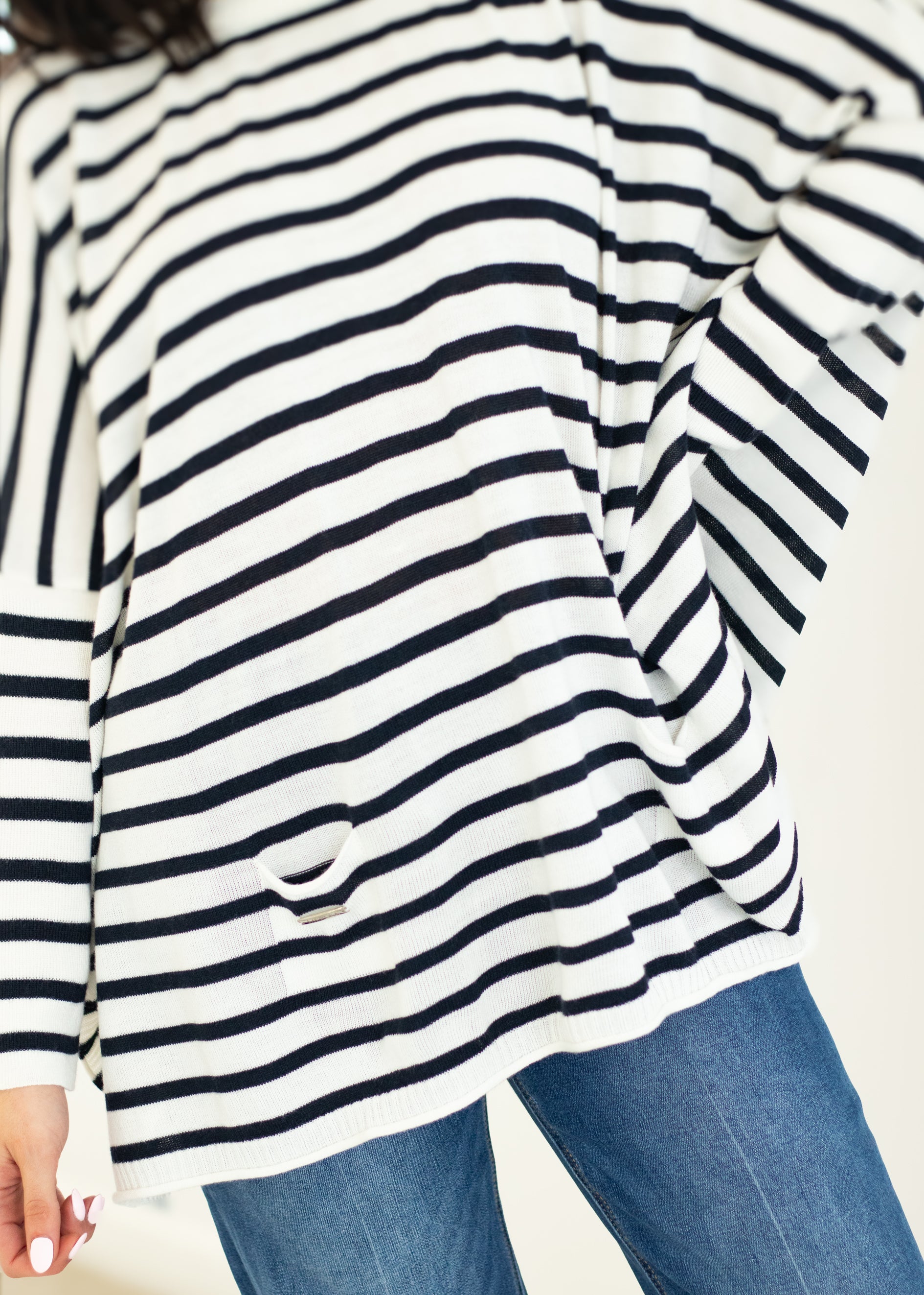 Close-up of a person wearing a black and white striped shirt with blue jeans on a white background