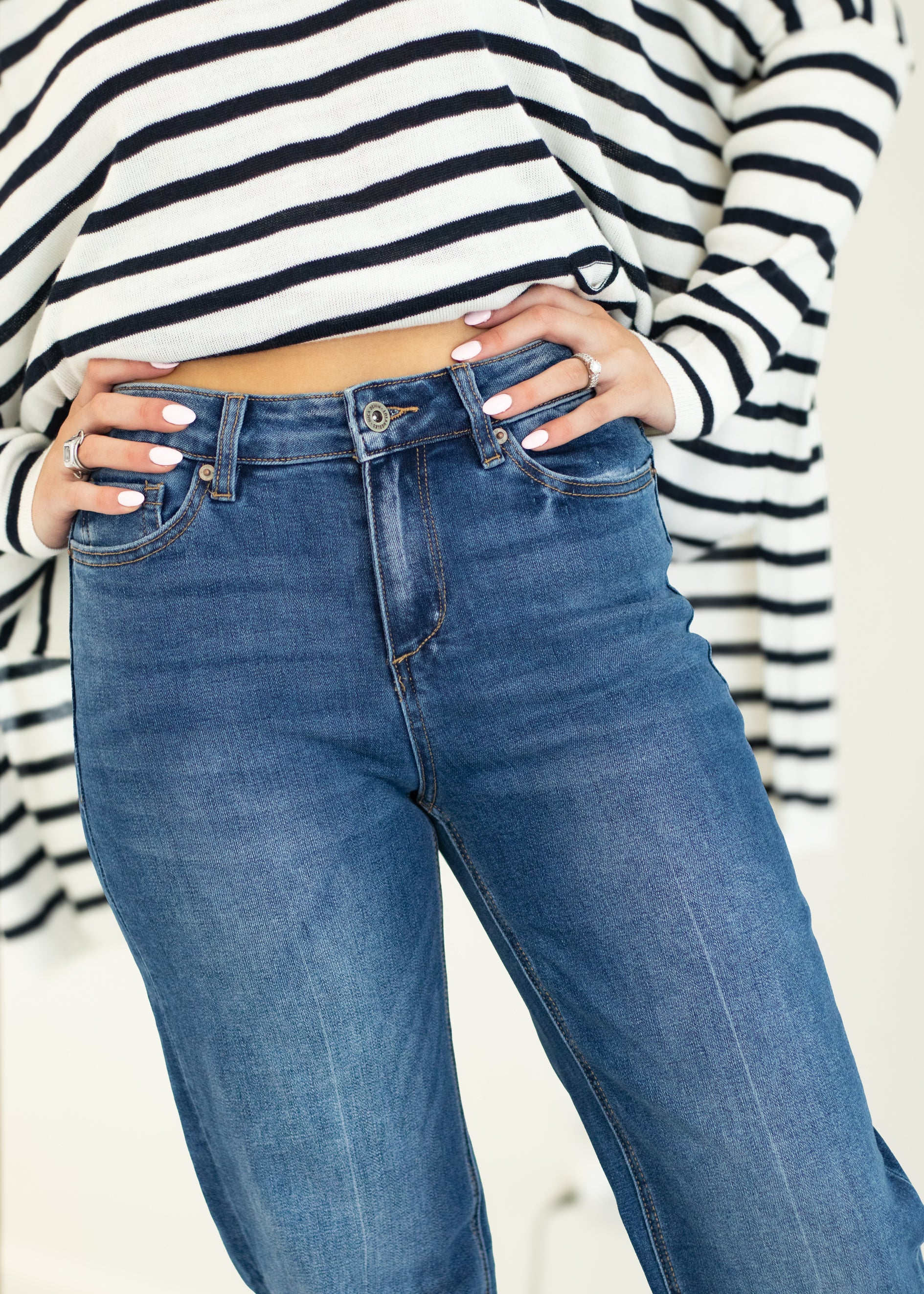 Person wearing blue jeans and a striped long-sleeve shirt on a plain background