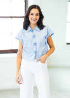 Woman wearing a light blue shirt and white pants indoors