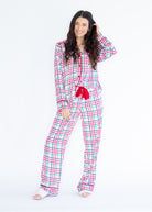 A woman modeling a two-piece long-sleeve pajama set with a pink, green, and white plaid pattern, featuring a red drawstring tie at the waist, photographed against a solid white background.