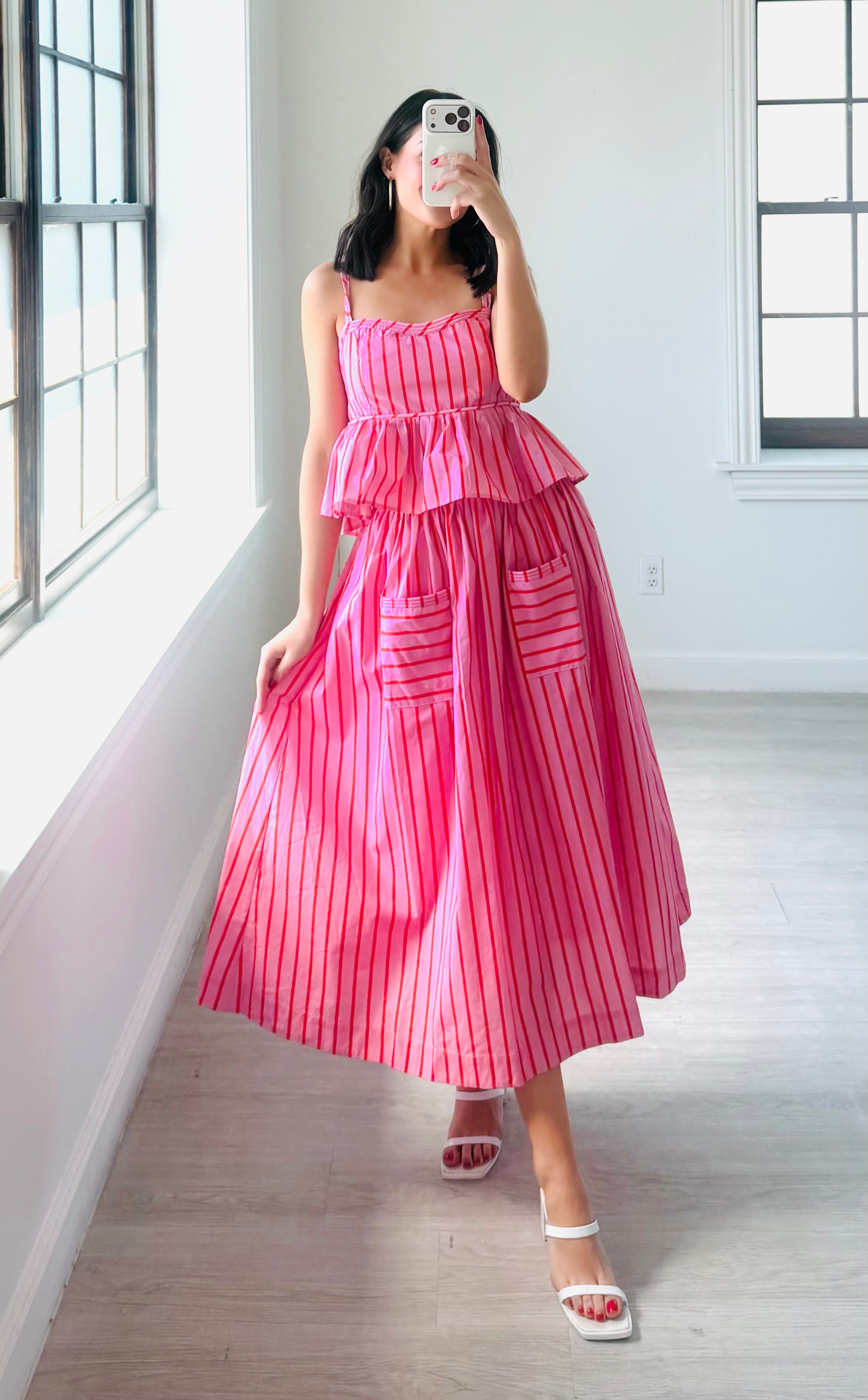 Woman wearing a pink and white striped dress against a plain background