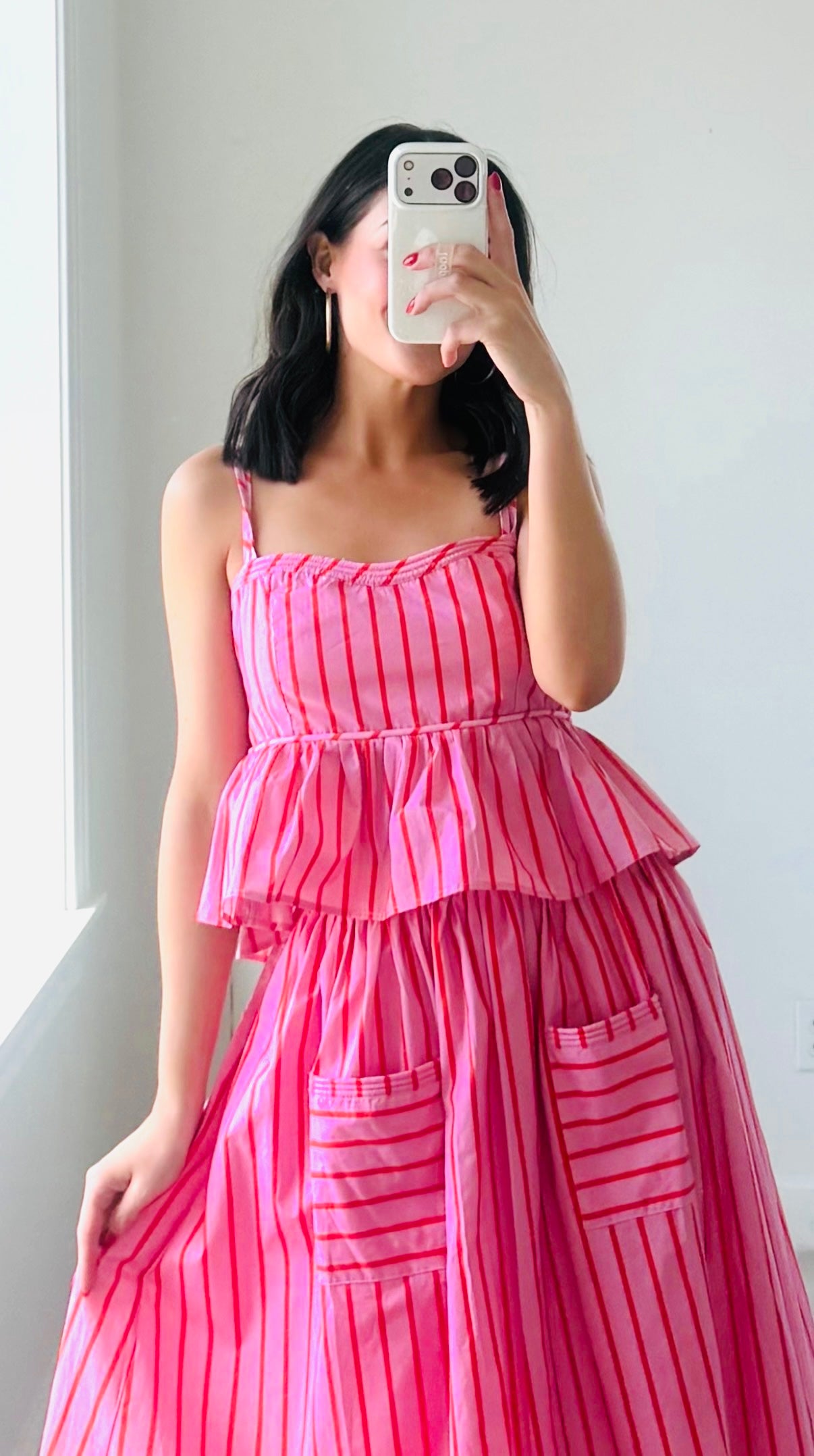 Woman wearing a pink and red striped top and matching skirt against a plain background