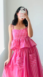 Woman wearing a pink and red striped top and matching skirt against a plain background