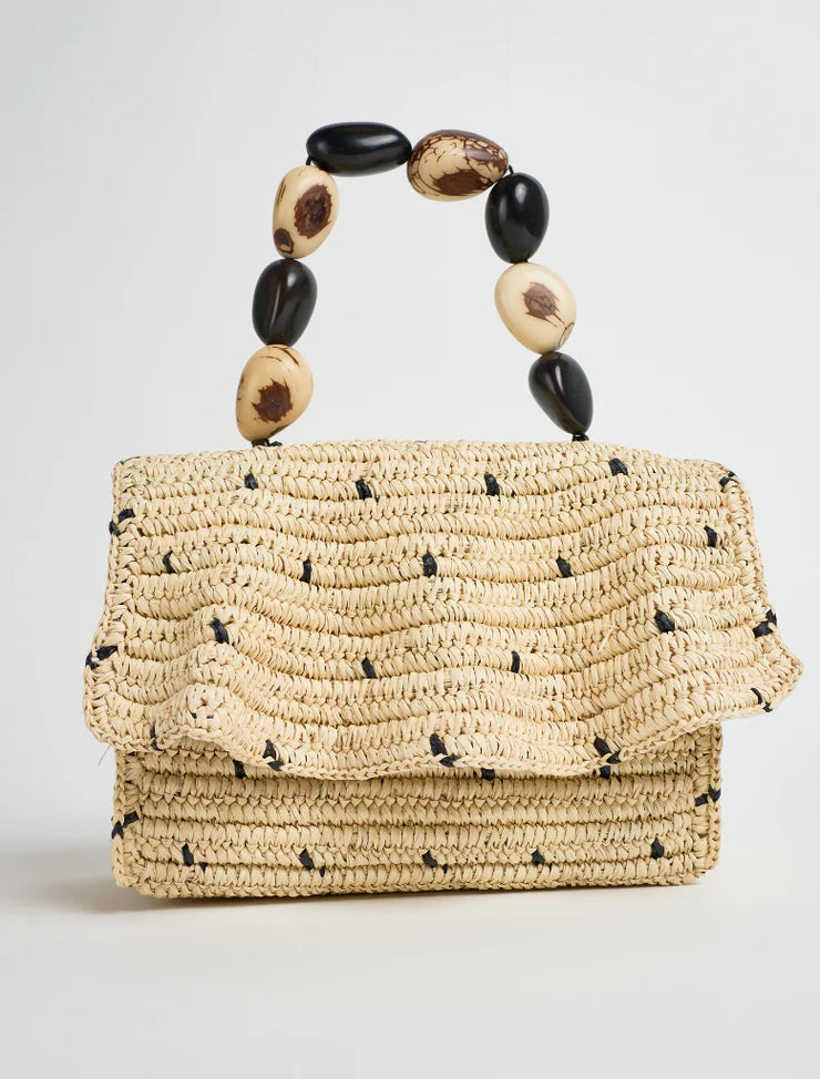 Woven handbag with a beaded handle on a light gray background